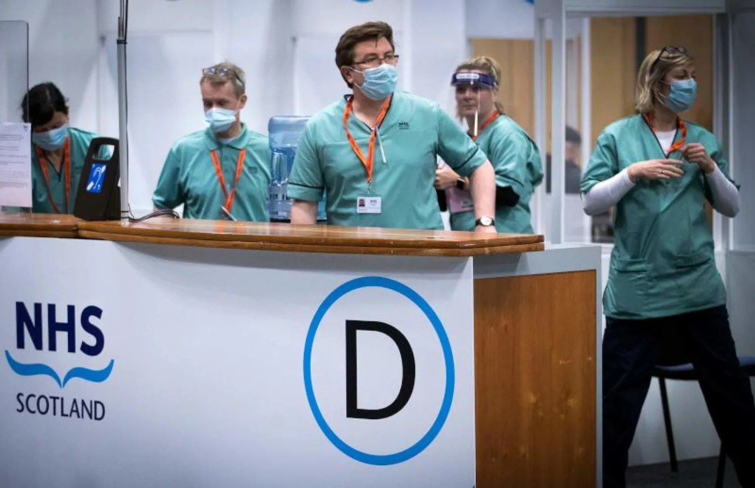 أعضاء فريق التطعيم ضد فيروس كورونا في مركز لتلقي اللقاح باسكوتلندا بمركز إدنبرة الدولي للمؤتمرات (أ.ف.ب)