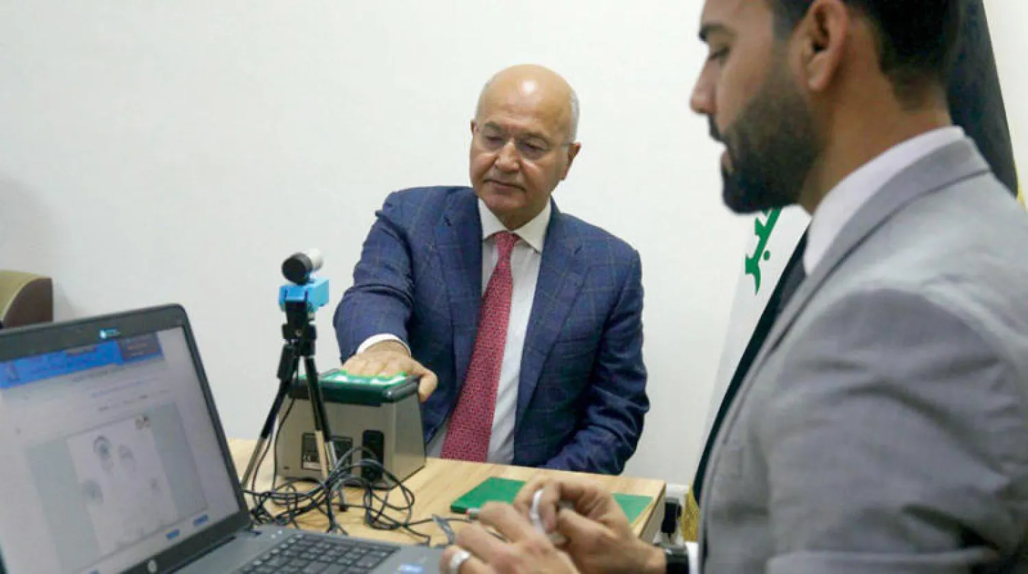 الرئيس العراقي برهم صالح يحدّث بطاقته البايومترية في أحد مراكز مفوضية الانتخابات في بغداد أمس (رئاسة الجمهورية)