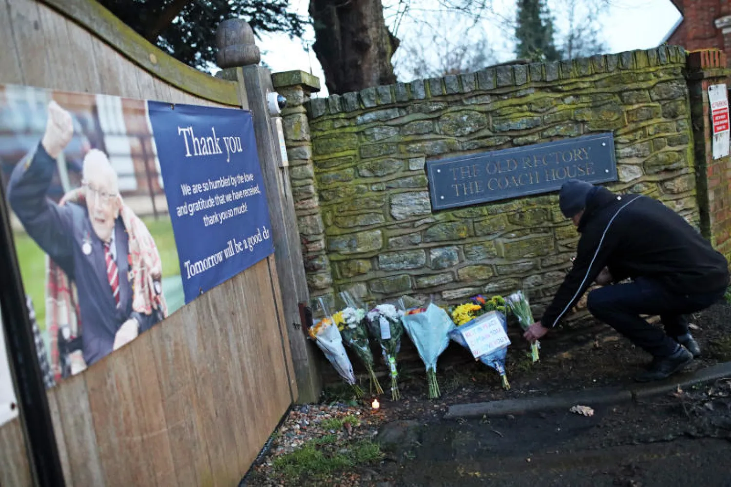 شخص يضع الزهور خارج منزل السير توم مور في بيدفورد (د.ب.أ)
