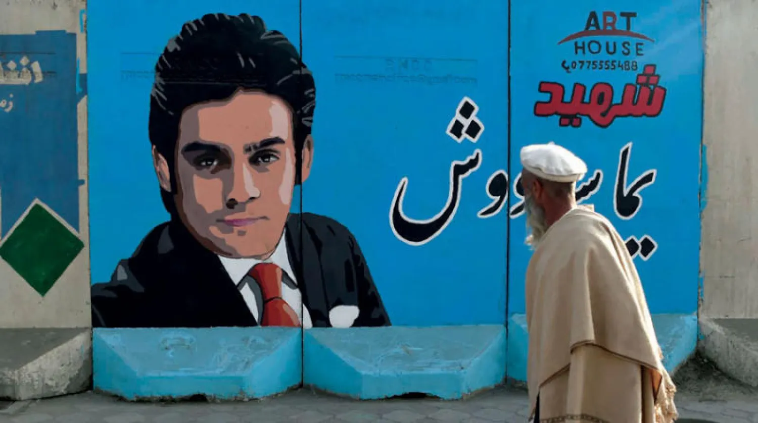 عجوز أفغاني يمر بجوار ملصق إعلامي وسط العاصمة كابل للمذيع التلفزيوني يامي سواش بمحطة «تولو»  الذي قتل في تفجير إرهابي نوفمبر الماضي (أ.ف.ب)