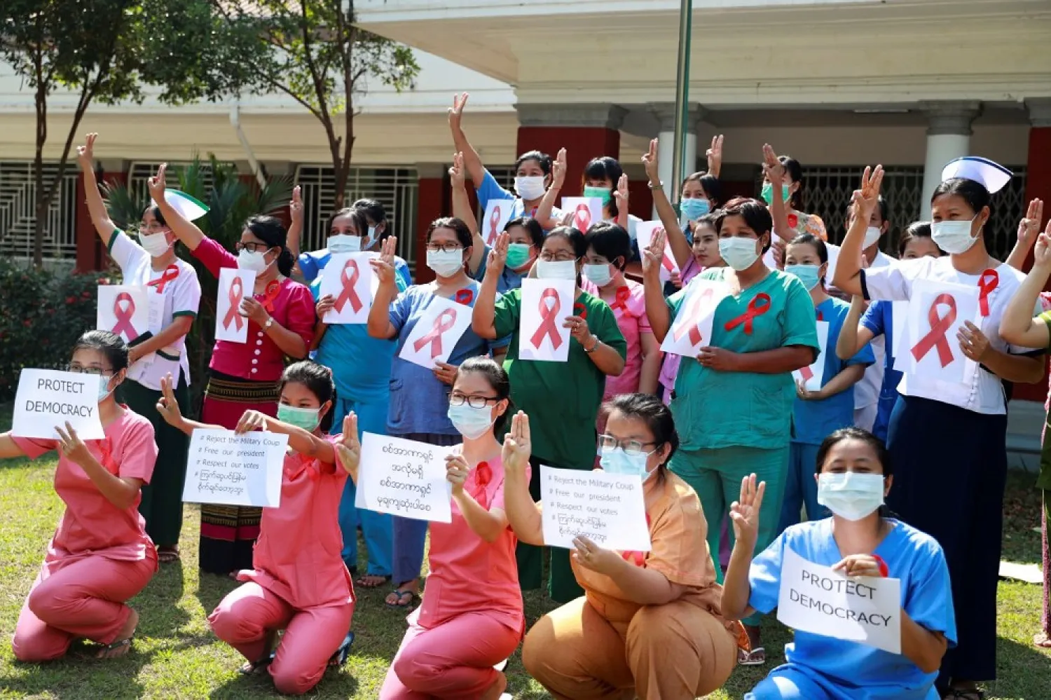 Staff of the University Hospital flash the three-finger protest gesture while holding signs that read: “Protect democracy” and “Reject the military coup, Free our president, Respect our votes” in Yangon, Myanmar, Feb 5. (AP)