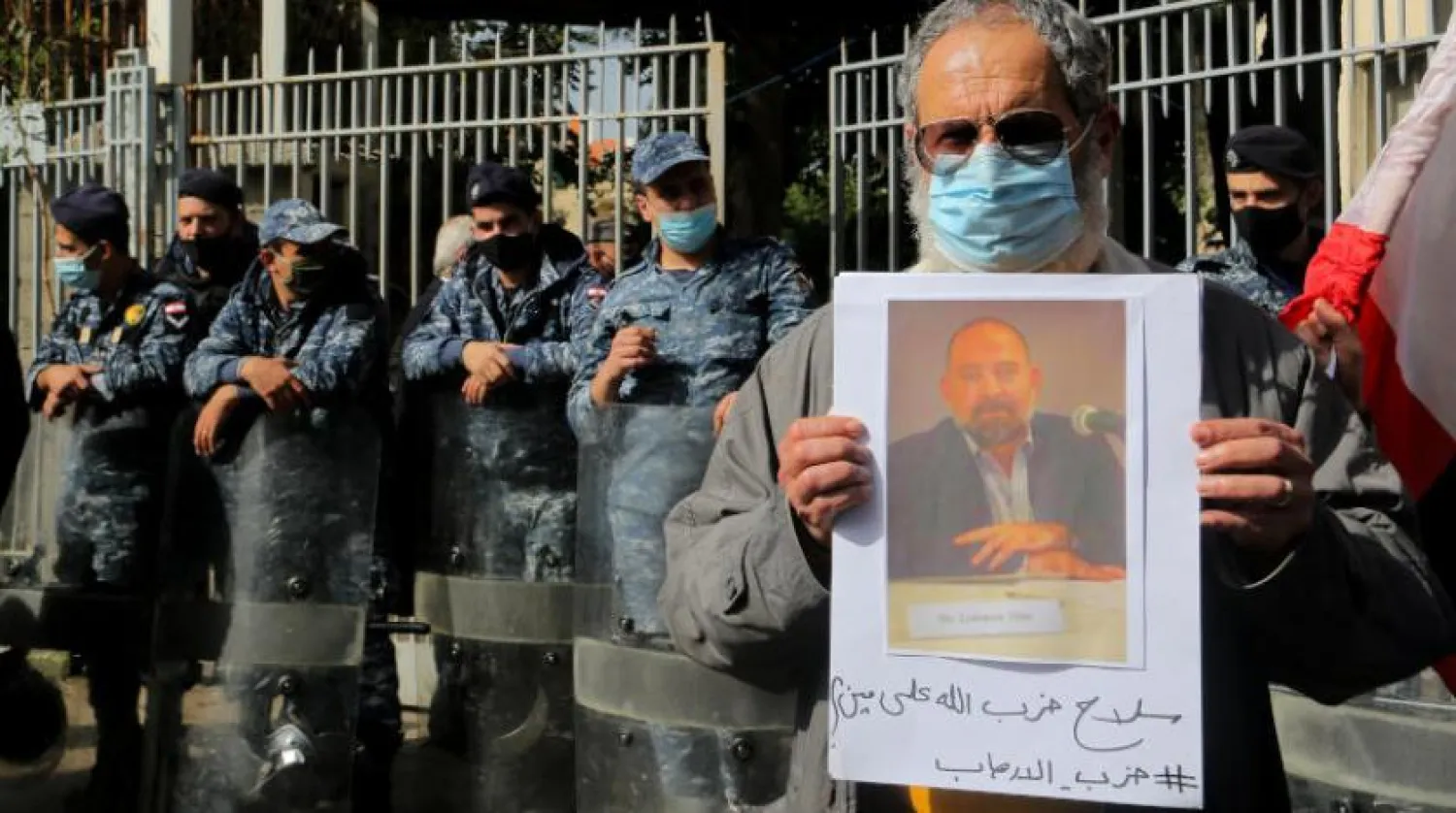 رجل يحمل صورة لقمان سليم خارج قصر العدل في بيروت (د.ب.أ)