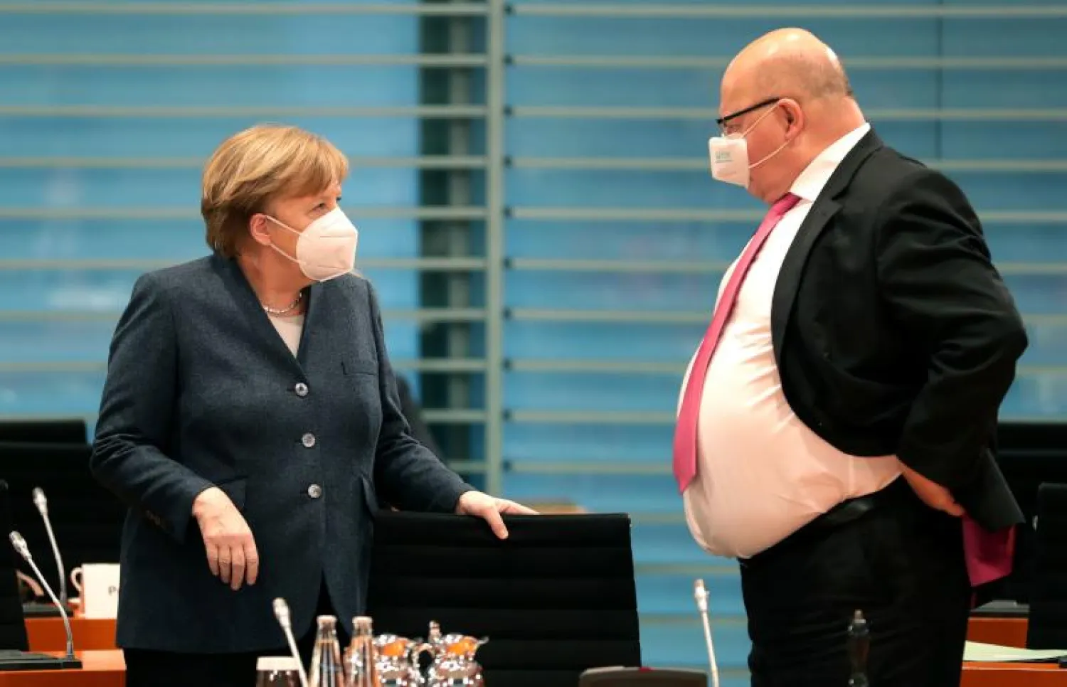 وزير الاقتصاد الألماني بيتر ألتماير (يمين) والمستشارة الألمانية أنجيلا ميركل في حديث قبل الاجتماع الوزاري الأسبوعي (أ.ف.ب)