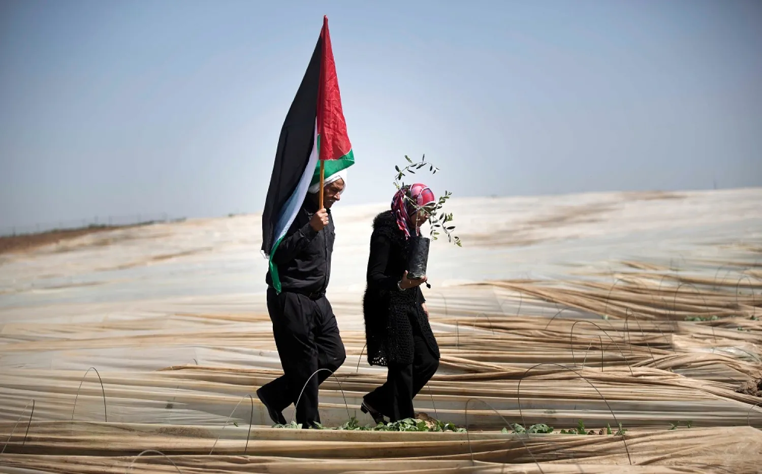 Palestinians walk through rows of greenhouses on "Land Day" during which people notably plant olive trees on March 29, 2014 near the Israeli border in Jabalia, in the northern Gaza. (AFP)
