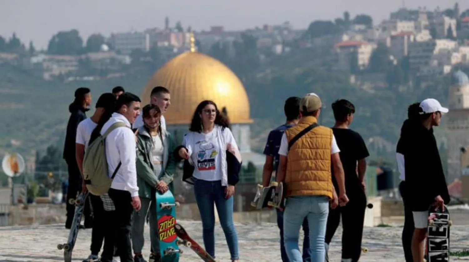 Kudüs’teki Filistinli gençler ile arkalarında Mescid-i Aksa havzası içindeki Kubbetu’s-Sahra’yı gösteren bir kare (Reuters)