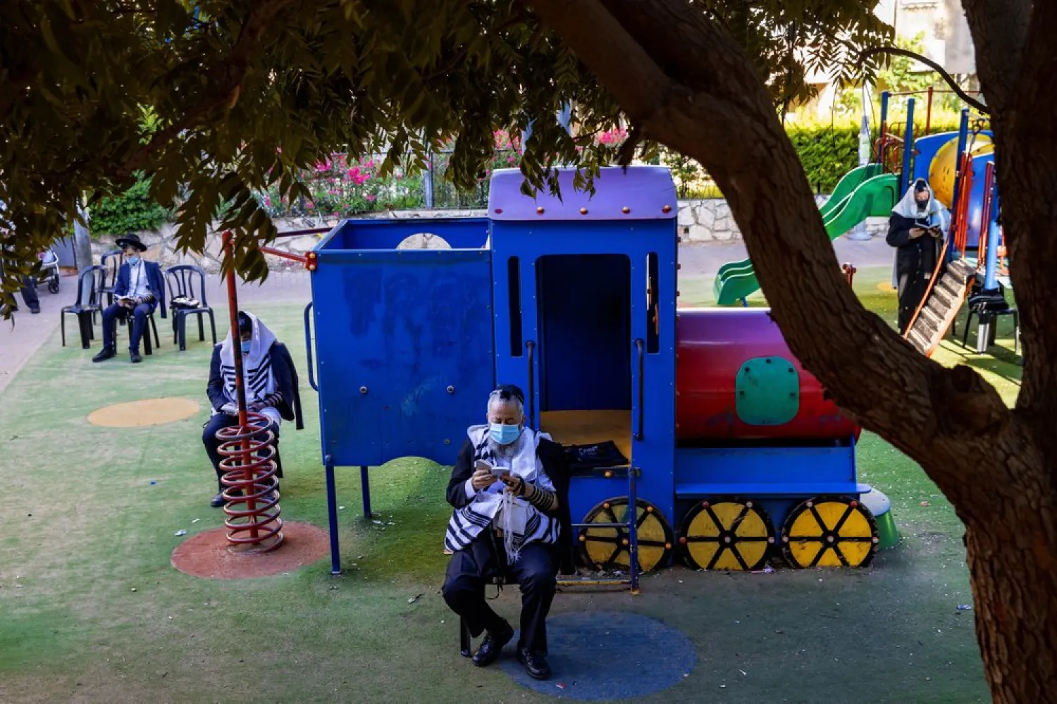 Ultra-Orthodox Jews pray at a playground next to their homes as they wear protective face masks help curb the spread of the COVID-19 coronavirus in Bnei Brak, Israel, Thursday, July 2, 2020.  (AP Photo/Oded Balilty)
