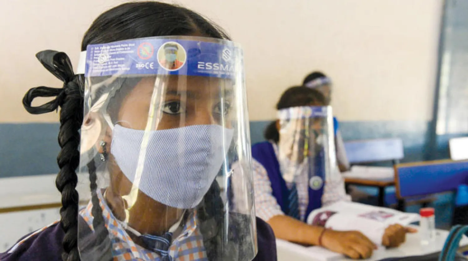 طالبة في الهند تضع كمامة وفوقها درعاً واقياً لمزيد من السلامة (أ.ف.ب)