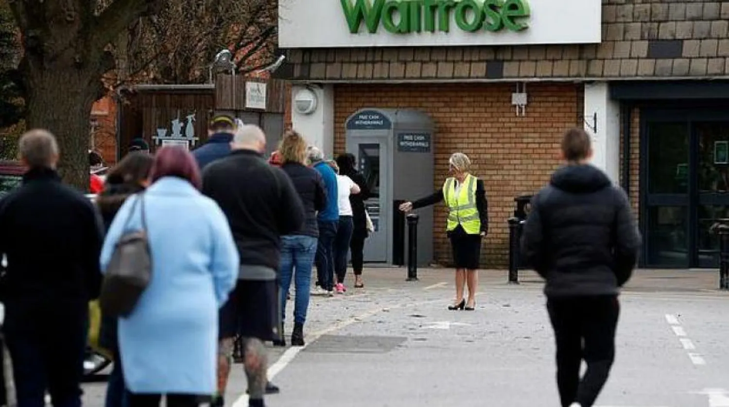 İngiltere’de bir marketin önünde sıraya giren insanlar (AFP)