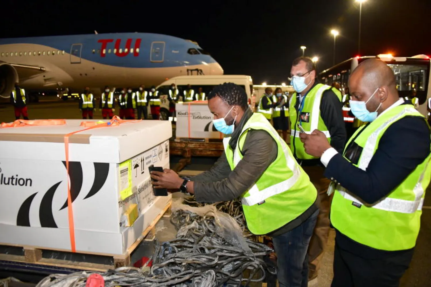 عمال يقومون بتفريغ منصات التحميل التي تحتوي على جرعات اللقاح جونسون آند جونسون عند وصولها إلى مطار أو آر تامبو في جوهانسبرغ (رويترز)