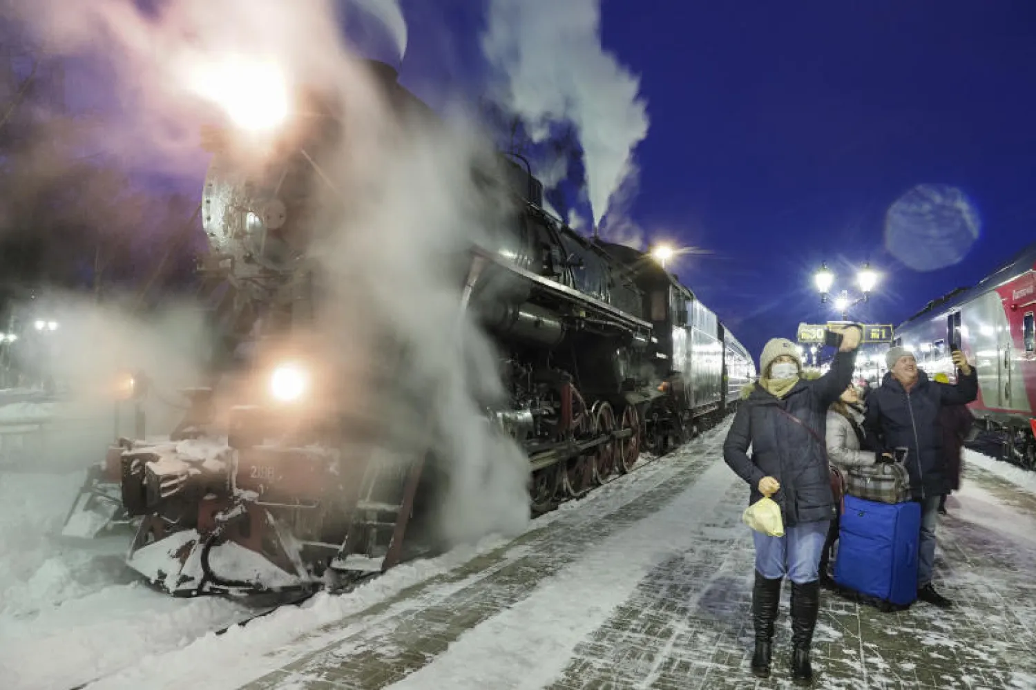 ركاب يلتقطون صور «سيلفي» إلى جوار قطار قديم في محطة لسكك الحديد في مدينة سورتافالا الروسية (أ.ب)