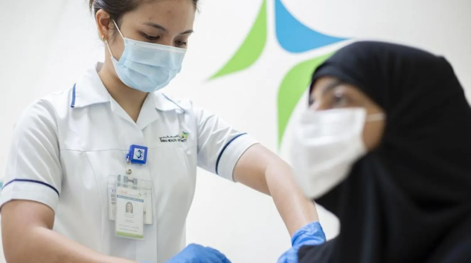 A medical worker injects a dose of a vaccine against the coronavirus disease (COVID-19) to a woman, in Dubai, UAE December 23, 2020. (Government of Dubai Media Office via Reuters)
