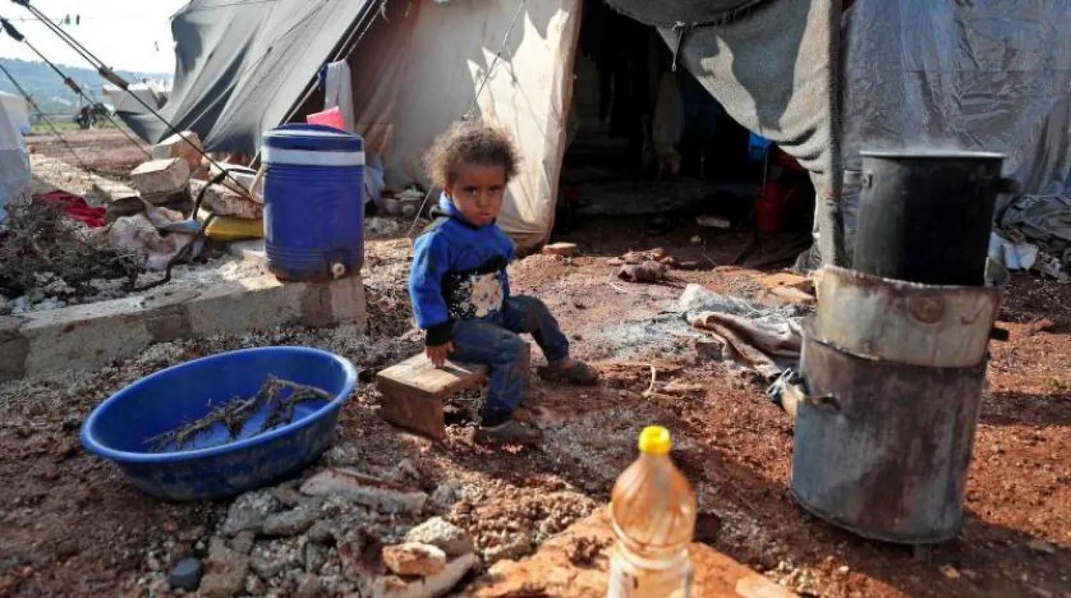 İdlib’deki mülteci kampındaki bir çadırın önünde oturan Suriyeli bir kız çocuğu (AFP)