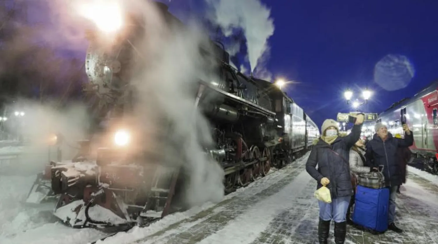 Yolcular, Rusya'nın Sortavala şehrinde bir tren istasyonunda eski bir trenin yanında "selfie" çekiyor (AP) 
