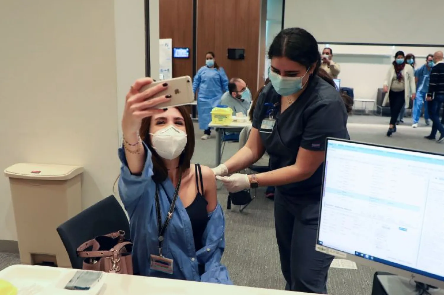 A woman takes a picture with her mobile phone as she receives the Pfizer-BioNTech vaccine against COVID-19 at the American University of Beirut's medical center on February 14, 2021. Mohamed Azakir/Reuters