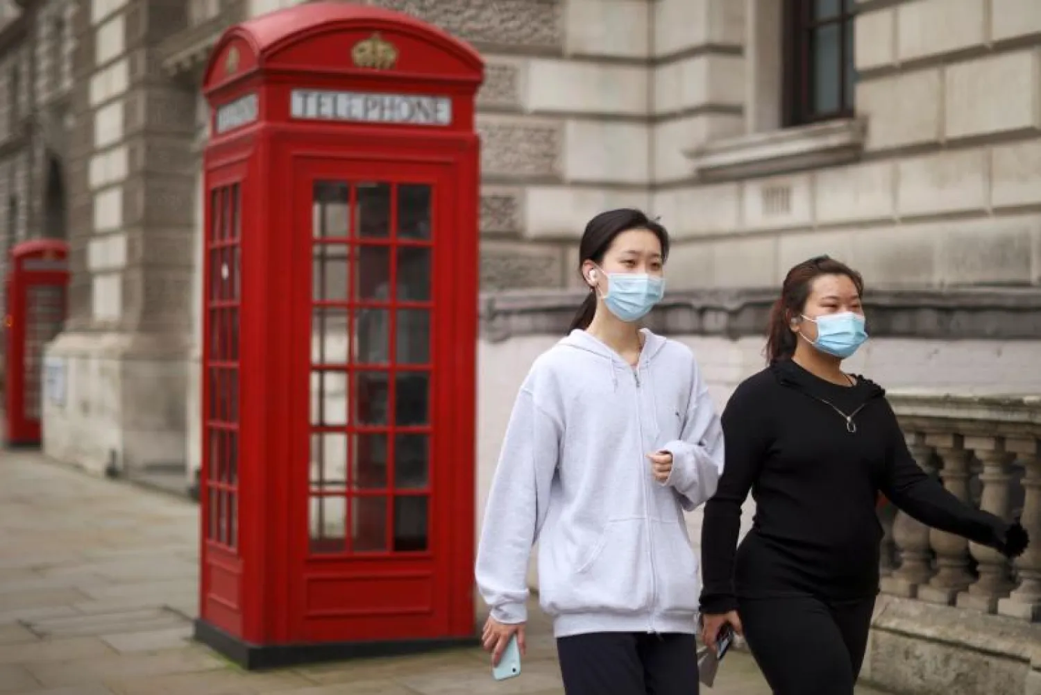 شابتان تضعان كمامتين للوقاية من «كورونا» في أحد شوارع لندن (أ.ف.ب)