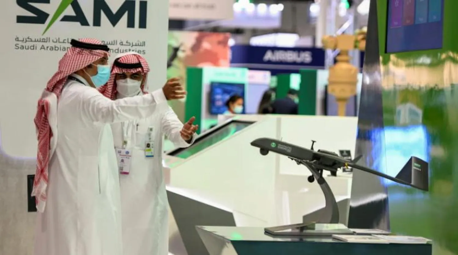 Abu Dabi’deki IDEX 2021 fuarında Suudi Arabistan Askeri Sanayi Sergisi önünde konuşan insanlar (Reuters)