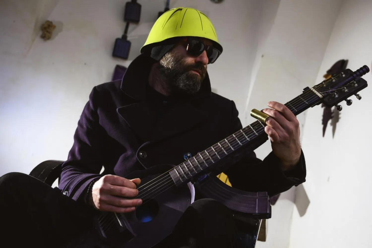 Srdjan Sarovic, visual artist and a war veteran, plays on a guitar made out of M70 rifle and a helmet, made by Serbian sculptor Nikola Macura at his studio, in Novi Sad on February 1, 2021.  Andrej Isakovic/AFP