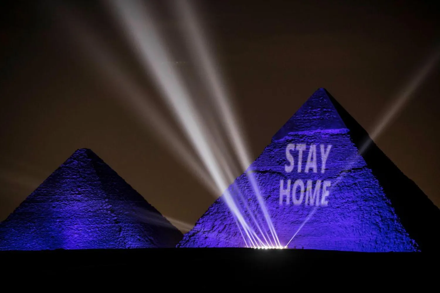 The Great pyramids lit-up with blue light and reading with a laser projection the message "Stay Home" on the Giza plateau outside the Egyptian capital of Cairo on April 18. (AFP)