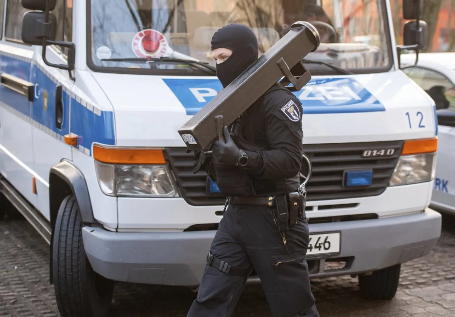 A police walks in front of a car during raids against an extremist network at the Maerkische Viertel neighborhood in Berlin, Thursday, Feb. 25, 2021 - (Christophe Gateau/dpa via AP)
