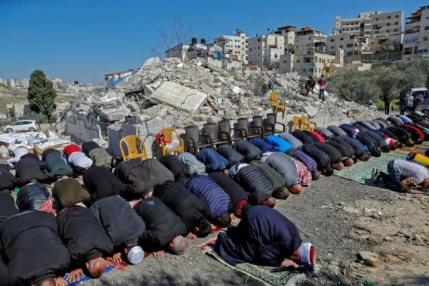 Palestinian Muslim worshippers attend Friday noon prayers in front of the rubble of buildings demolished by Jerusalem municipality workers, reportedly built without an Israeli construction permit, in the mostly-Arab East Jerusalem neighborhood of Issawiya, on February 26, 2021. | AFP