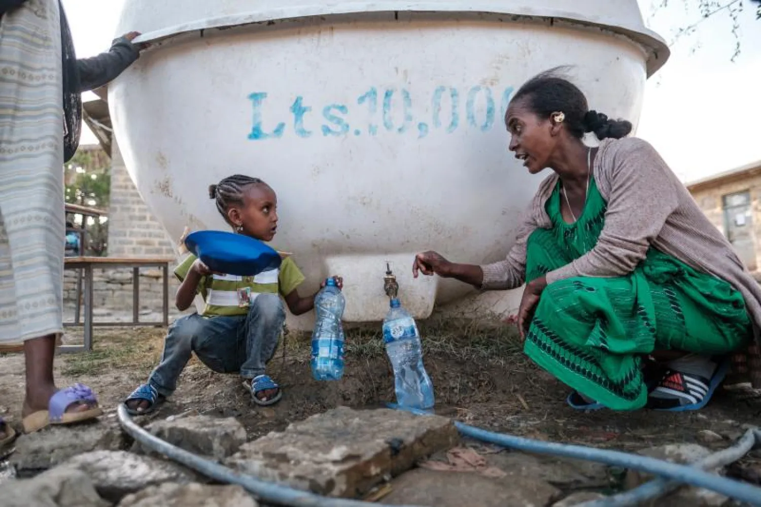 امرأة نازحة وطفل من ولاية تيغراي يتحدثان أثناء قيامهما بجمع المياه (أ.ف.ب)