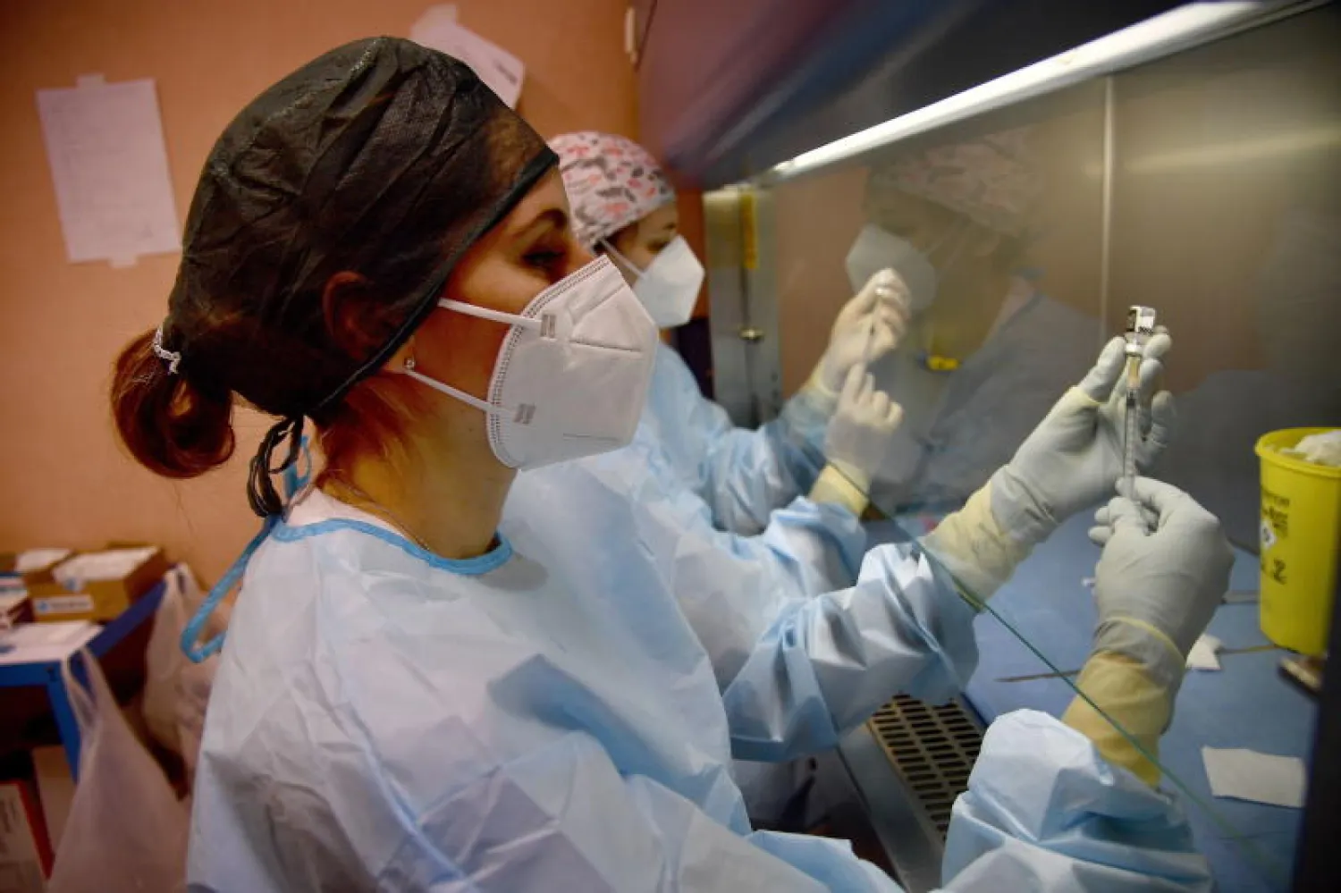 عاملون صحيون يجهزون جرعات لقاح في مستشفى بجنوة الإيطالية (إ.ب.أ)