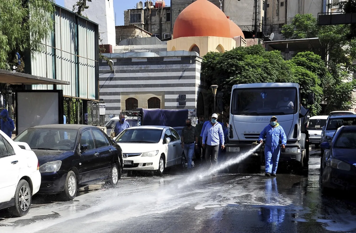 A Syrian worker disinfects a street to prevent the spread of coronavirus in Damascus, Syria, August 3, 2020. (SANA via AP)