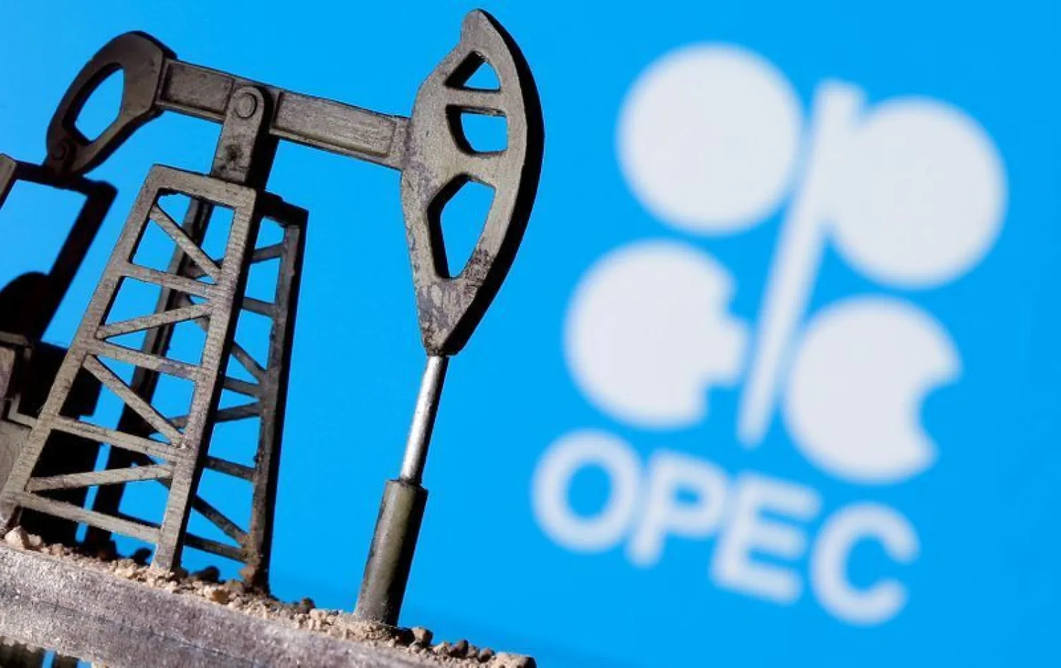 A 3D printed oil pump jack in front of the OPEC logo | REUTERS