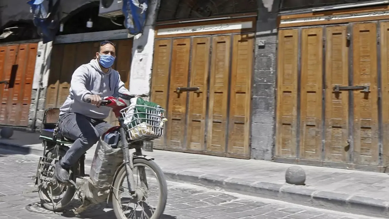 A Syrian man, wearing a protective face mask to protect against the coronavirus (COVID-19) pandemic, rides his motorcycle down a street near the Old City of the capital Damascus on April 14, 2020. (AFP)