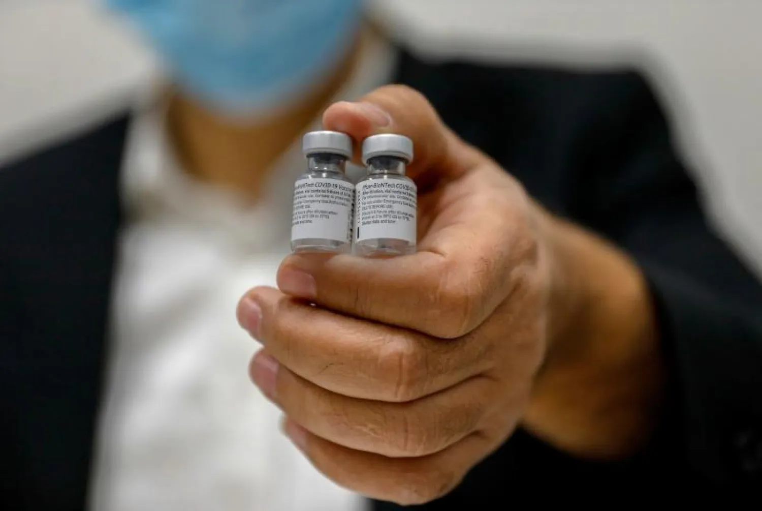 ممرض يحمل جرعتين من لقاح لفيروس «كورونا» فى القدس (أ.ف.ب)