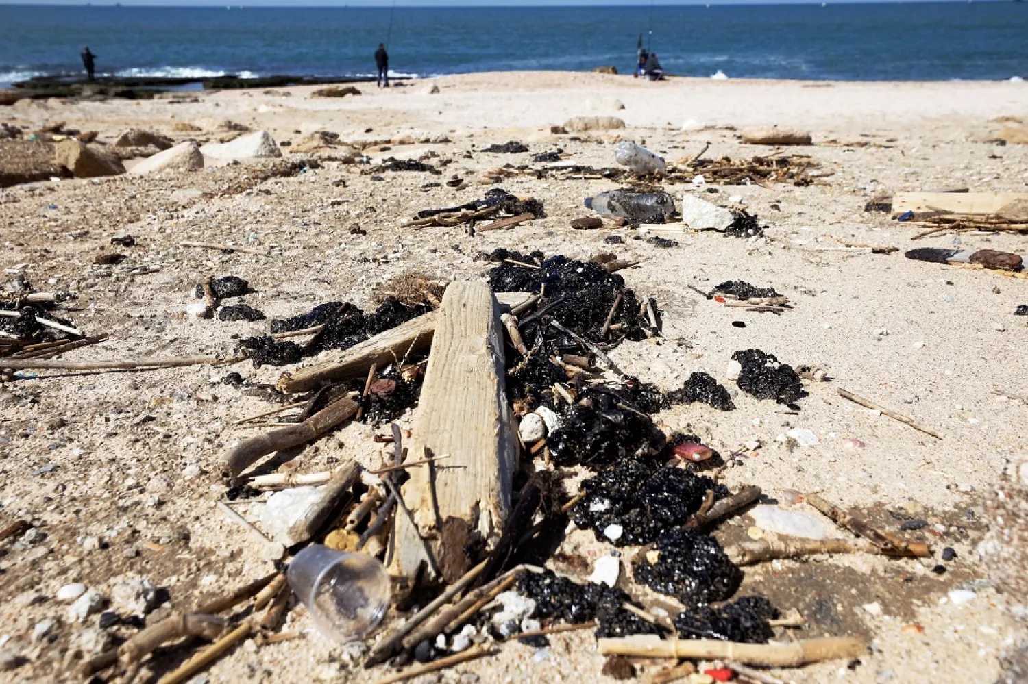 Clumps of tar are seen on the sand after an offshore oil spill drenched much of Israel's Mediterranean shoreline with tar, at a beach in Ashdod, southern Israel, Feb. 21, 2021. (Reuters)