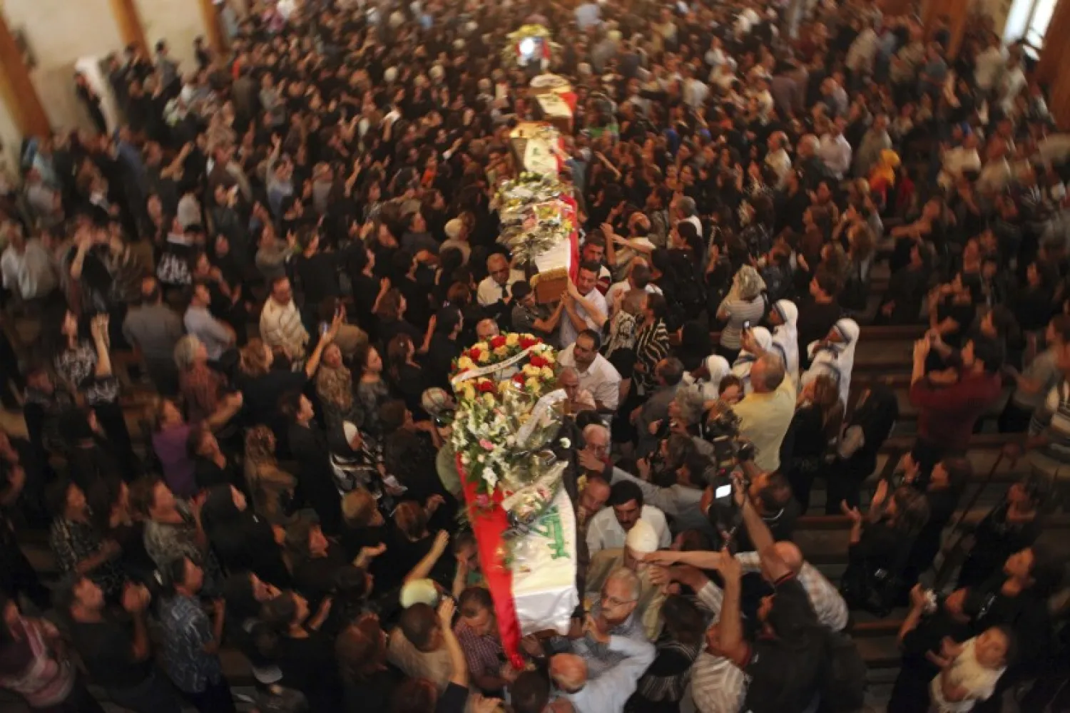 In this Tuesday Nov. 2, 2010 file photo, mourners carry the coffins of slain Christians during their funeral in Baghdad, Iraq, who were killed Sunday when gunmen stormed a church during mass and took the entire congregation hostage. (AP Photo/Khalid Mohammed, File)