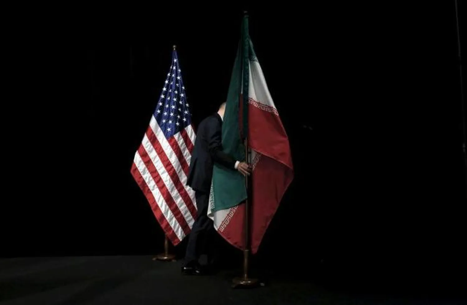 A staff member removes the Iranian flag from the stage after a group picture with foreign ministers and representatives of the US, Iran, China, Russia, Britain, Germany, France, and the European Union during the Iran nuclear talks at the Vienna International Center in Vienna, Austria July 14, 2015. REUTERS/Carlos Barria/File Photo