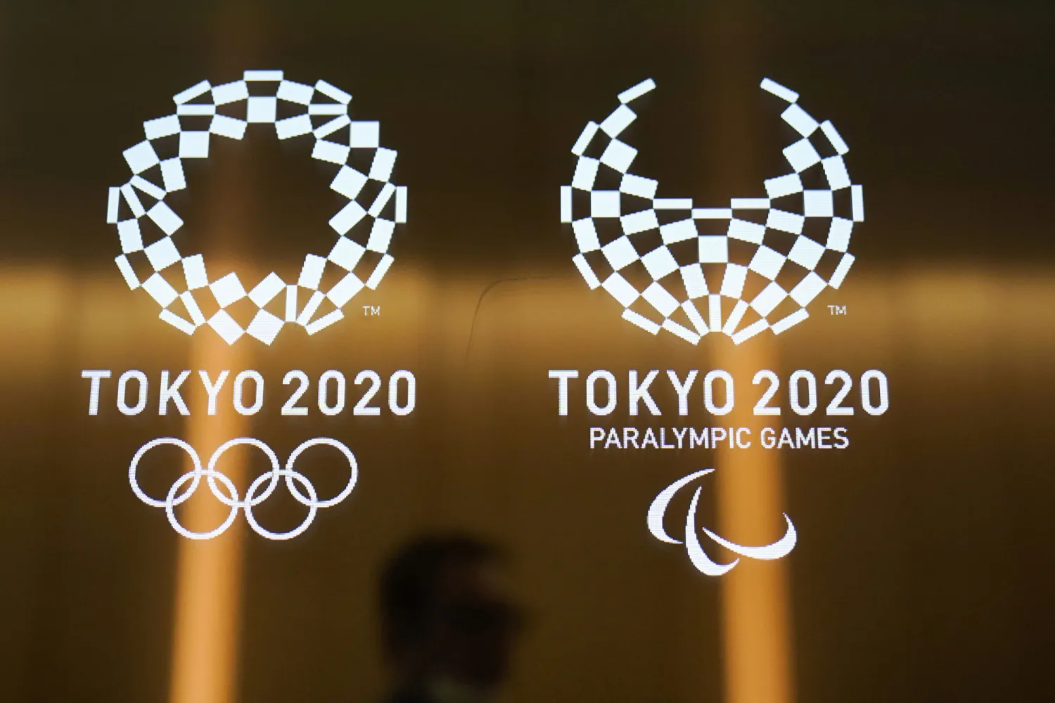 A man walks past the logos for the 2020 Tokyo Olympics and Paralympics on June 11, 2019. AP file photo