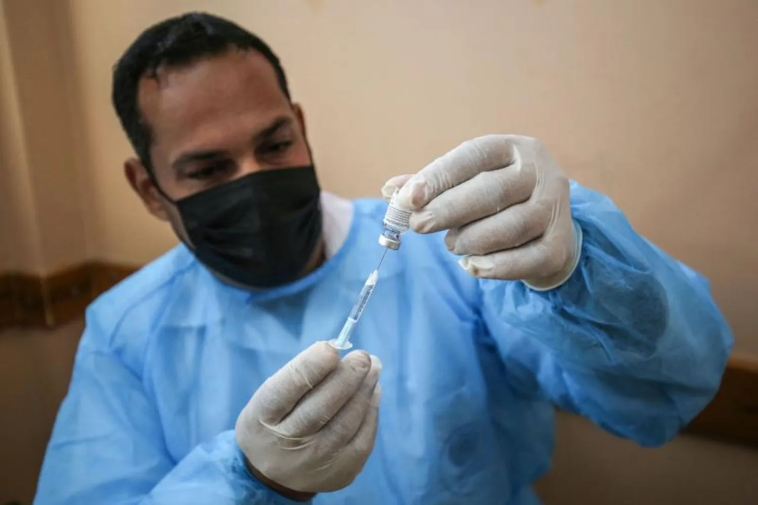 عامل صحي في الأونروا يجهّز جرعة من لقاح مضاد لكورونا (أ.ف.ب)