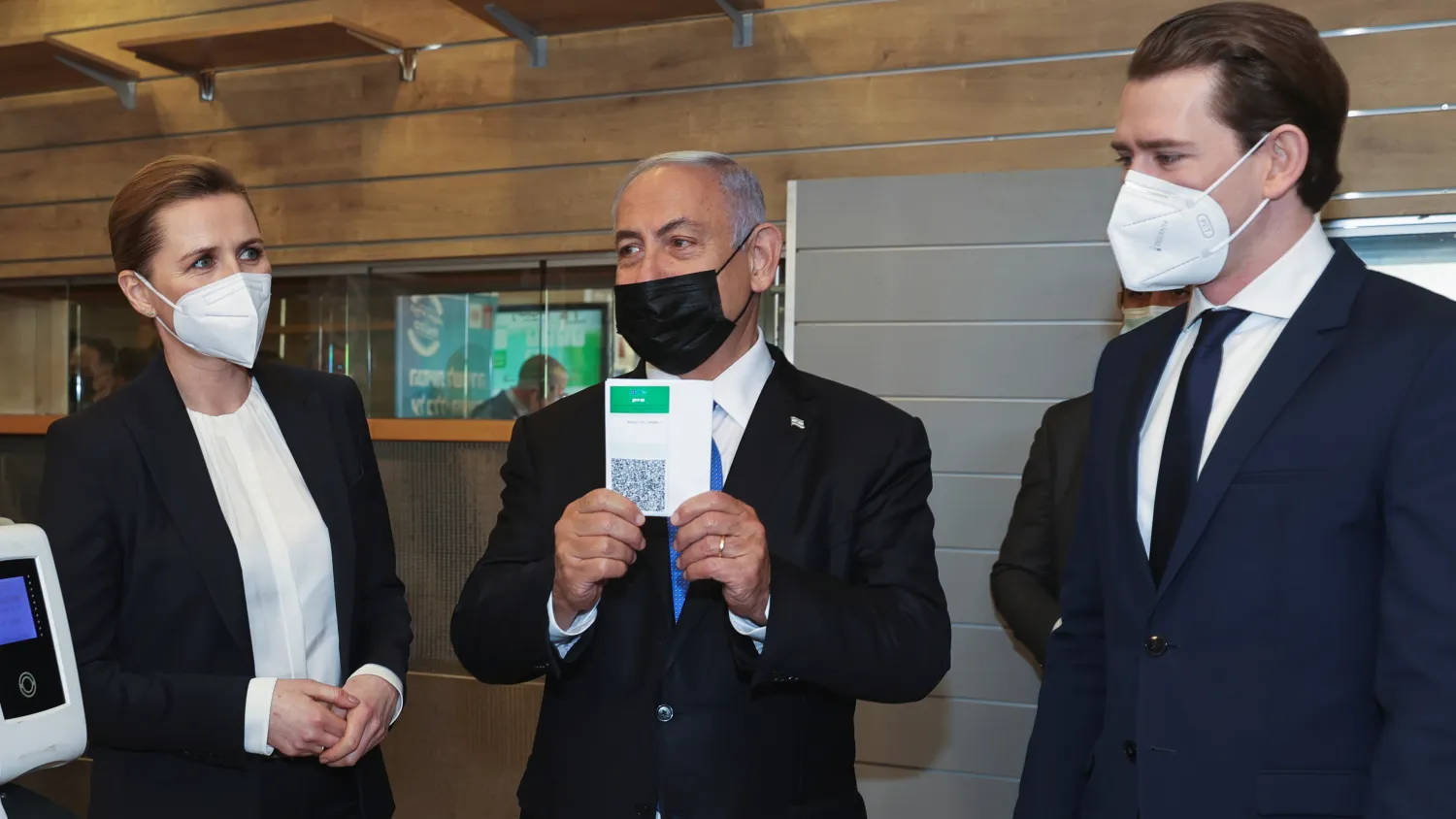 Israeli Prime Minister Benjamin Netanyahu holds up a document, that is part of the "Green Pass" system, which grants certain privileges to citizens who have had both doses of the vaccine against the coronavirus disease (COVID-19) or have recovered from COVID-19, as Austrian Chancellor Sebastian Kurz and Denmark's Prime Minister Mette Frederiksen stand nearby during a visit at a gym to observe the "Green Pass" system, in Modiin, Israel March 4, 2021. Avigail Uzi/Pool via REUTERS
