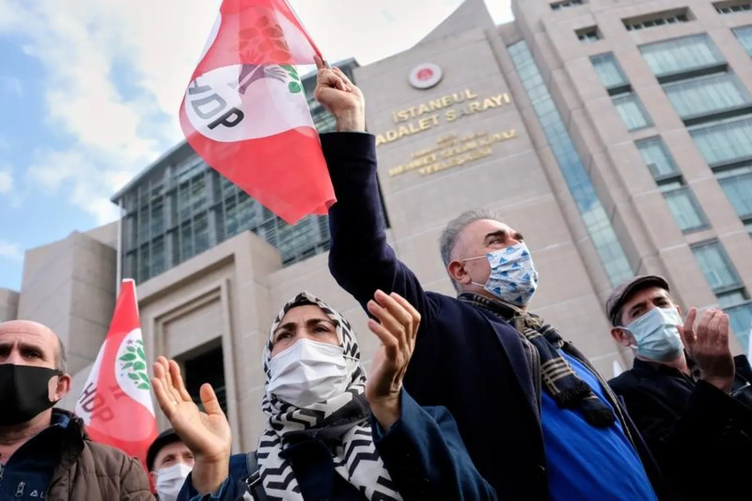 Supporters of Selahattin Demirtas, a jailed former co-leader of the HDP, wave party flags as they gather outside the Istanbul Justice Palace, in Istanbul, Turkey February 3, 2021. (Reuters)