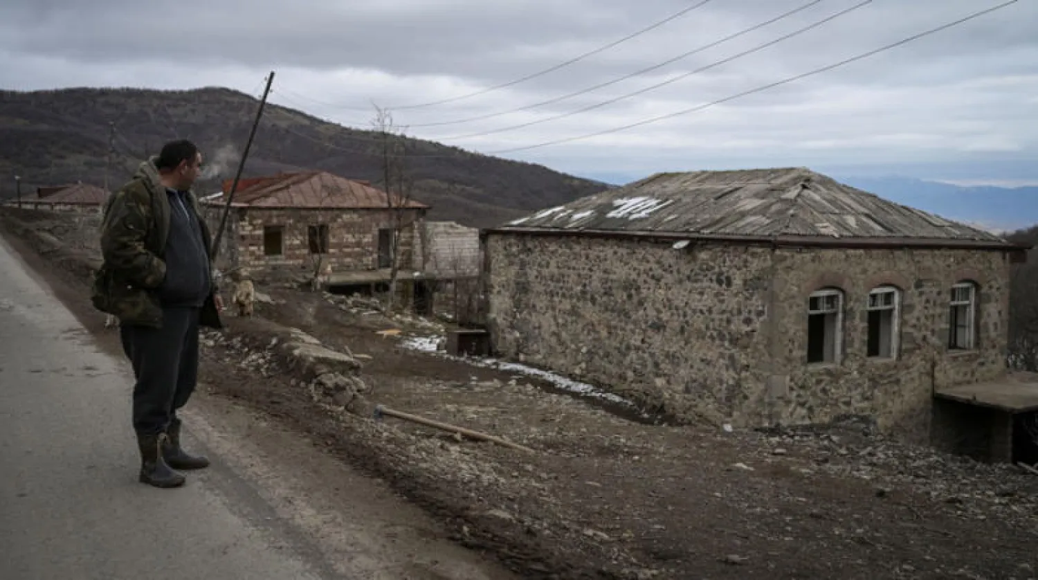 مزارع في قرية شورنوخ ينظر إلى بيته القديم الذي أصبح على الجانب الآخر من الحدود الدولية (أ.ف.ب)