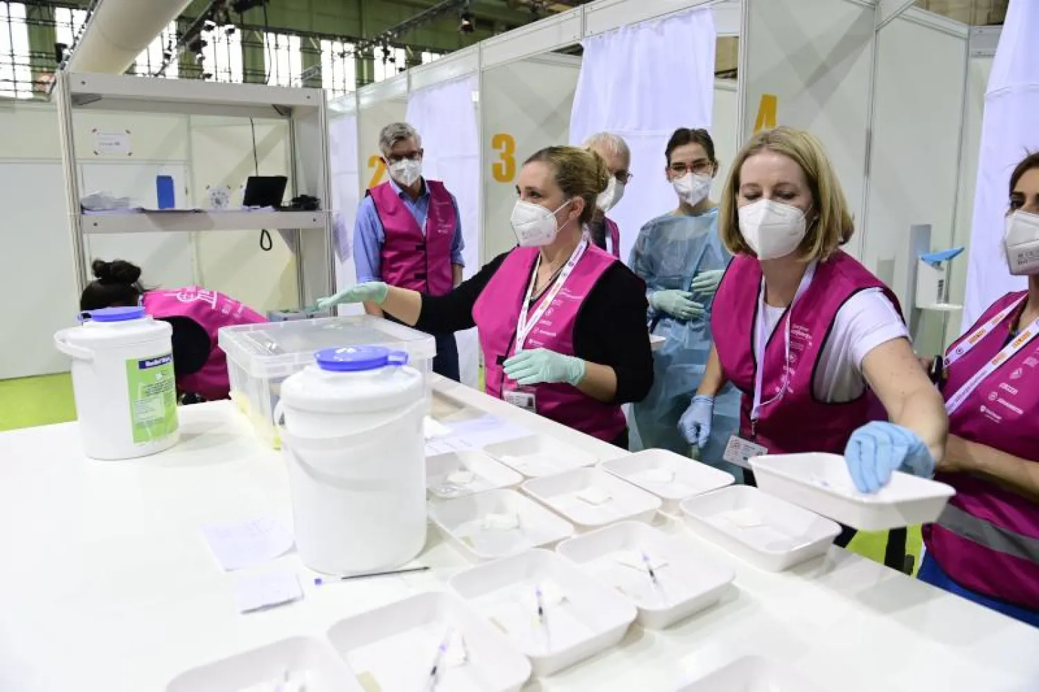 عاملون صحيون يحضرون أطباقاً تحتوي على محاقن مع لقاح  ضد فيروس «كورونا» بمركز تطعيم جديد في مطار «تمبلهوف» السابق في برلين (أ.ف.ب)