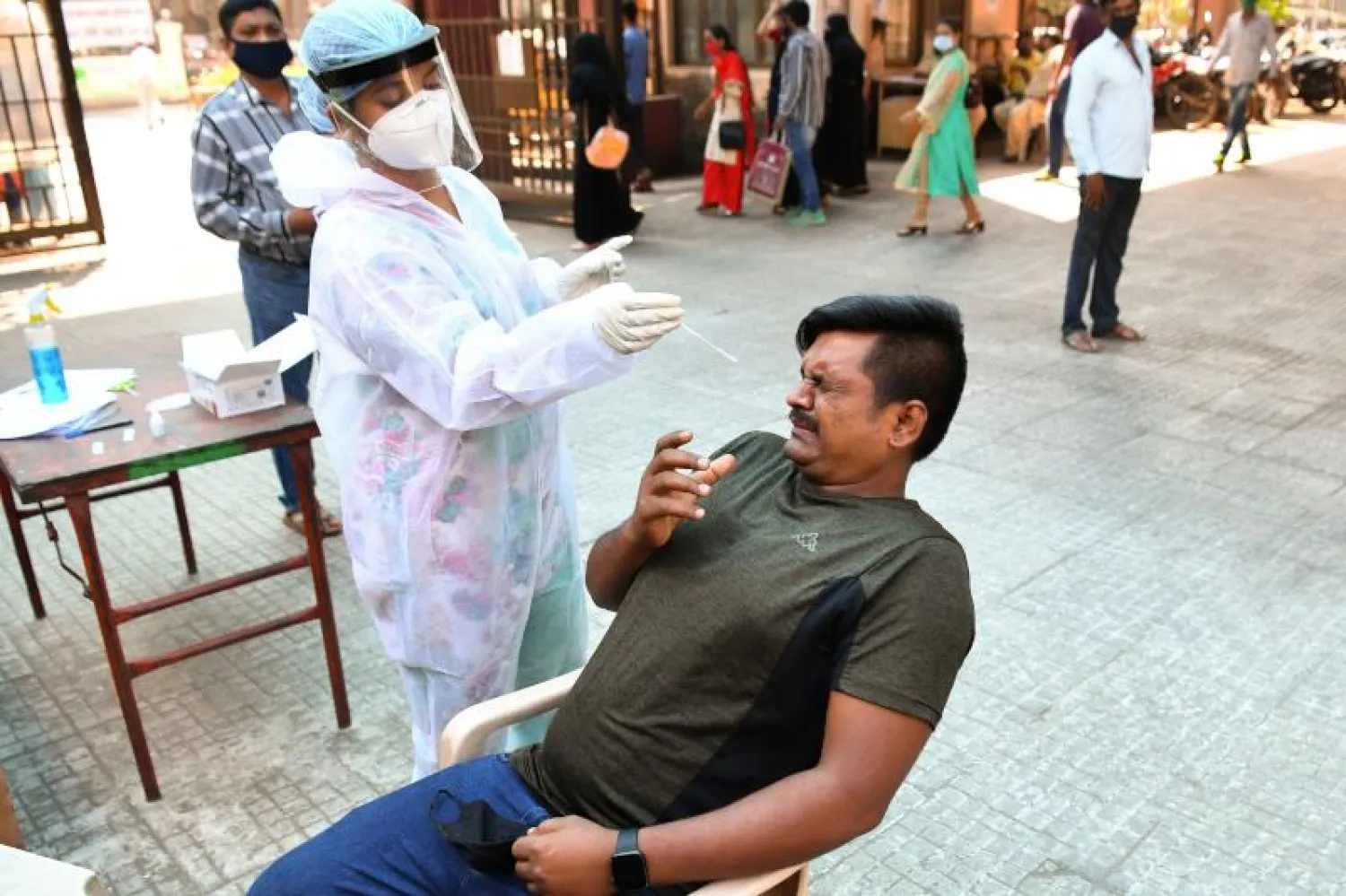 ممرض يأخذ مسحة للكشف عن فيروس «كورونا» من رجل في مومباي (أ.ف.ب)