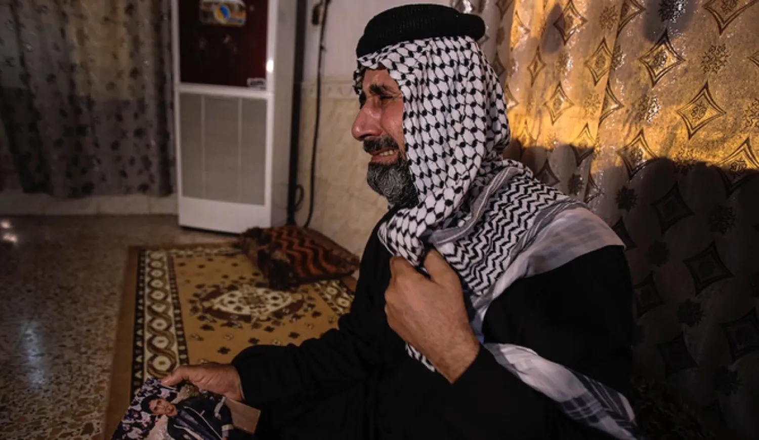Jasb Hattab Aboud, father of the kidnapped protester Ali Jasb, cries as he holds his son's picture in his home un the town of Amara, Iraq. (File/AP)
