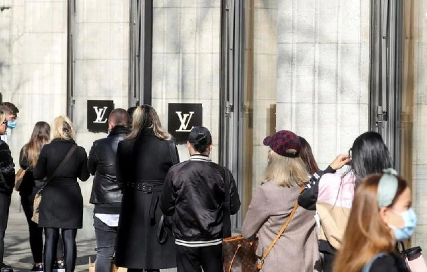 FILE PHOTO: Shoppers queue in front of a Louis Vuitton store after the Swiss government relaxed some of its COVID-19 restrictions, as the spread of the coronavirus disease continues, at the Bahnhofstrasse shopping street in Zurich, Switzerland March 1, 2021. REUTERS/Arnd Wiegmann/File Photo
