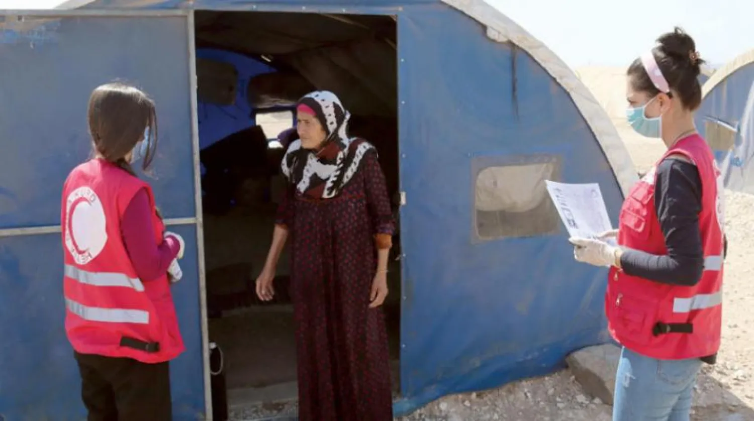 Red Crescent volunteers speak to a refugee at the Washokani camp. (Asharq Al-Awsat)