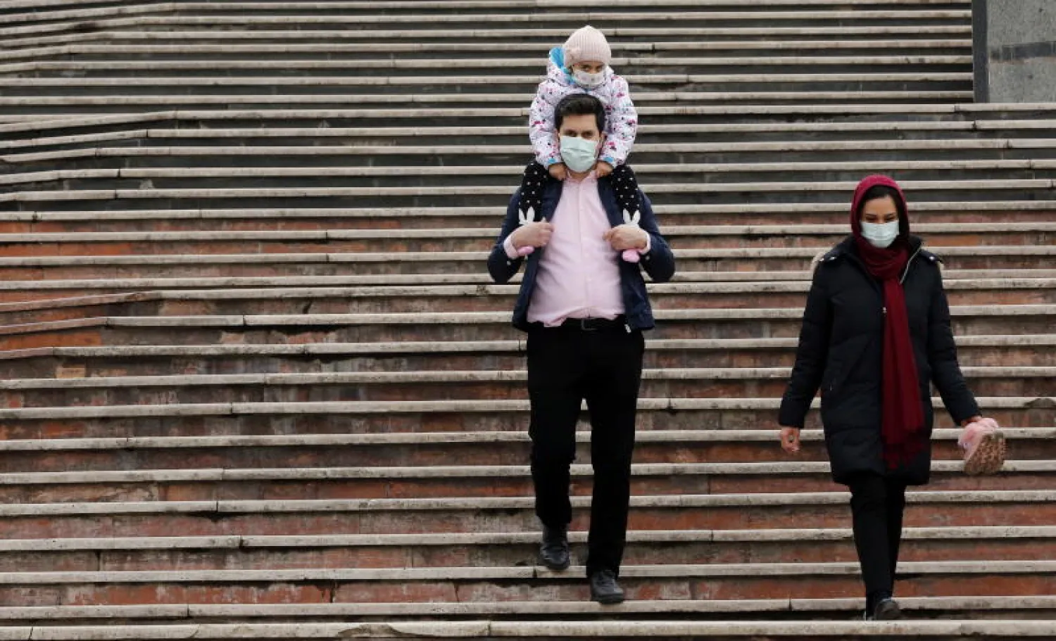 أشخاص يرتدون الكمامات في طهران (إ.ب.أ)