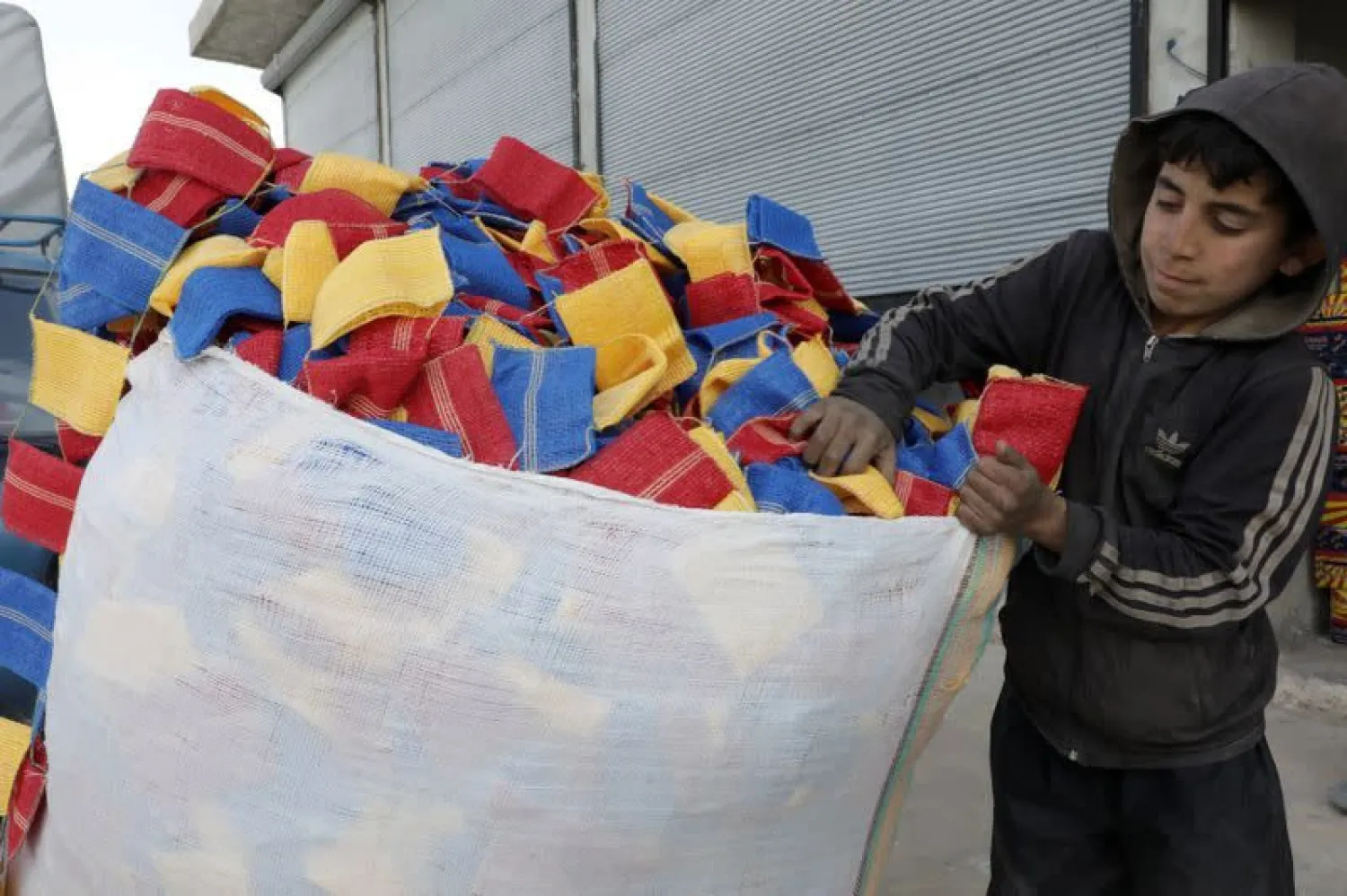 Mohammed Abu Rdan puts dishcloths in a bag, in front of the cleaning products factory, northern Aleppo. (Reuters)