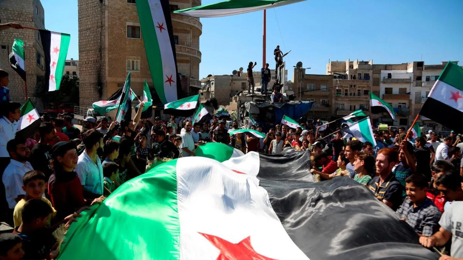 Syrian protesters, wearing the colors of opposition, attend an anti-government demonstration in the opposition-held northern Syrian city of Idlib. (AFP)