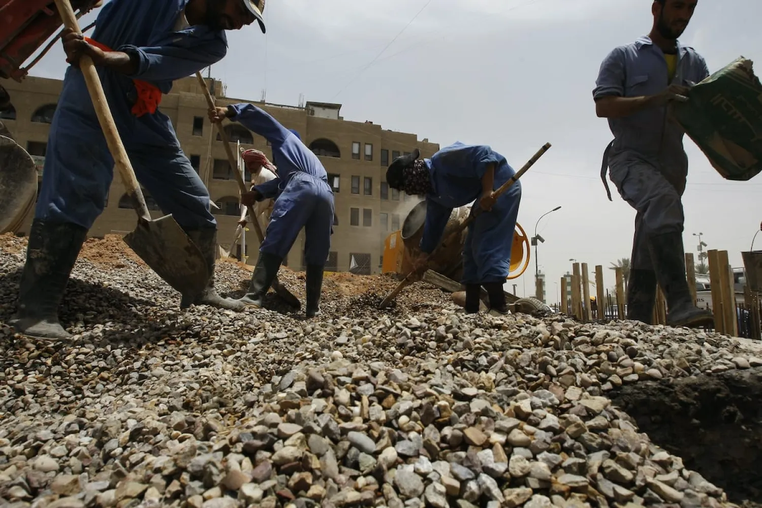Construction workers shovel stones at a building site in Baghdad, Iraq. (AFP file photo)