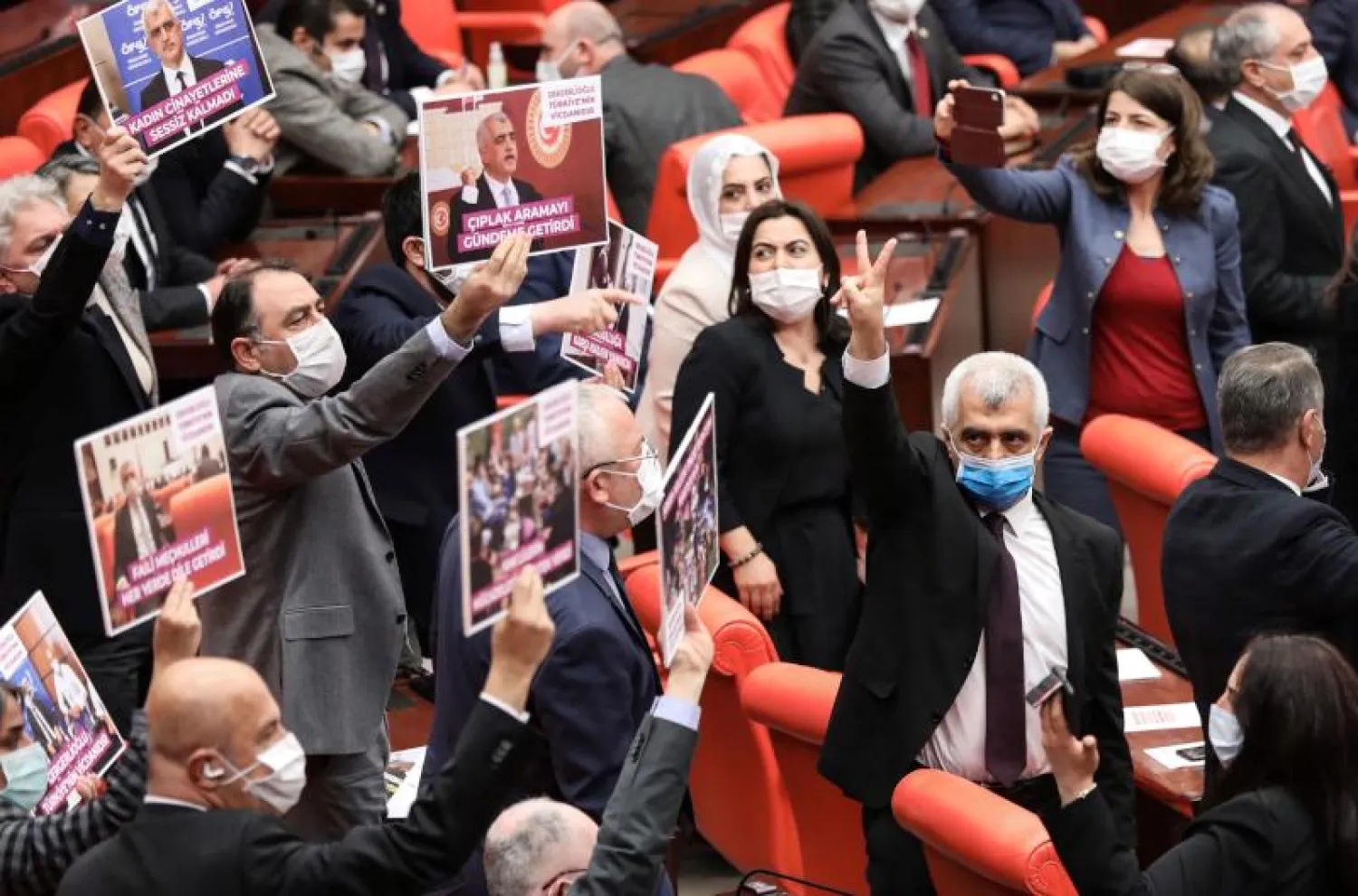 النائب عمر فاروق جرجرلي أوغلو يشير بعلامة النصر وسط أعضاء البرلمان الذين يرفعون لافتات عقب قرار إسقاط عضويته (أ.ف.ب)