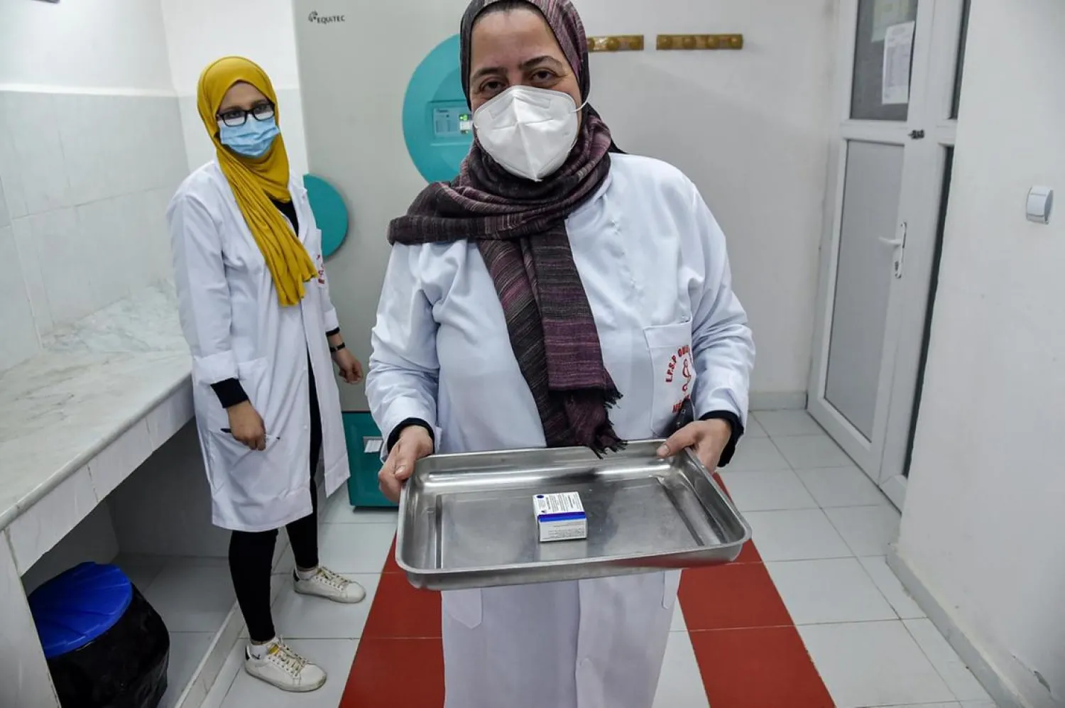 A medical worker walks with a pack of Russia's Sputnik V vaccine for COVID-19 coronavirus disease extracted from a refrigerator at a clinic in the city of Blida, about 45 kilometers southwest of the Algerian capital, on January 30, 2021. (Photo by RYAD KRAMDI / AFP)