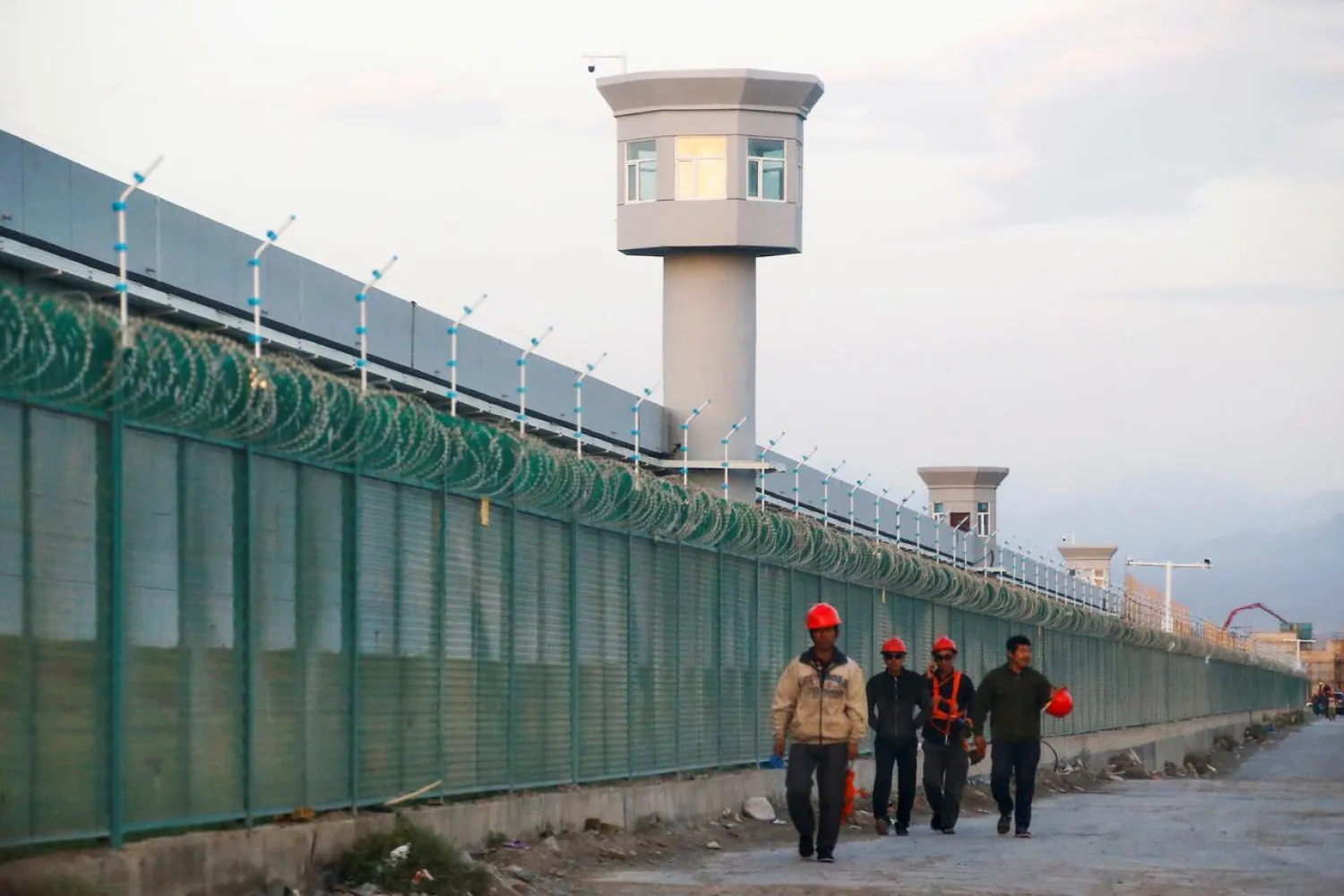 FILE PHOTO: Workers walk by the perimeter fence of what is officially known as a vocational skills education center, under construction in Dabancheng in Xinjiang Uighur Autonomous Region, China September 4, 2018. REUTERS/Thomas Peter/File Photo